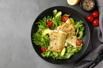 Dish with salad with white sea fish, avocado and cherry tomatoes. Copy space.