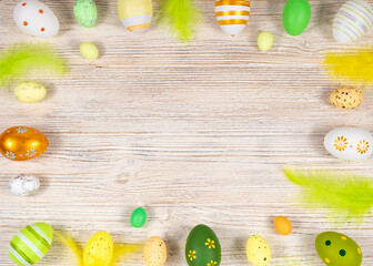 Easter frame with eggs and feathers on a light wooden background. Minimal concept. View from above. Card with copy space for text.