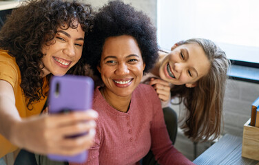 Fototapeta premium Happy african american mother and teen daughters using smartphone apps for shopping social media