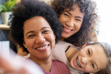 Happy african american mother and teen daughters using smartphone apps for shopping social media