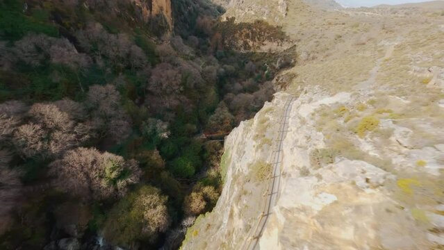 FPV drone proximity flight along edges of mountains surrounding a valley near Monachil, Spain