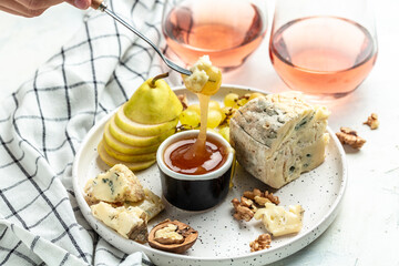 Wine and cheese still life. wine and assorted Cheese Plate with fruit. Grapes Pear Nuts Cashew Cheese with mold Gorgonzola. A glass of wine with cheese