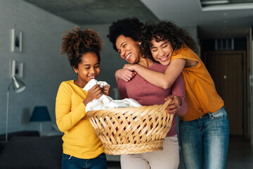 Happy multiethnic teenage children are smiling while do household with mother at home.