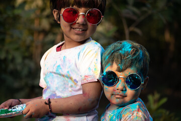 Indian Festive Theme - Happy Asian Indian Kids Baby Boy And Girl Having Fun With Non Toxic Herbal Holi Color Powder Called Gulal Or Abir Rang Abeer During Hindu Ritual Dol Purnima