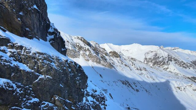 snowy mountains and rocky cliffs in a winter wonderland in the alpes drone 4k orbit reveal shot.
