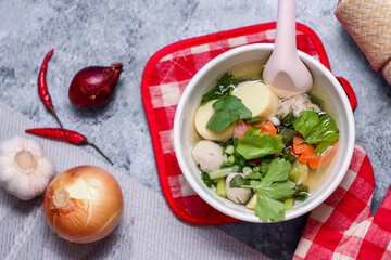 Boiled tofu and minced pork served in white cups with red checkered saucers placed on a white table.