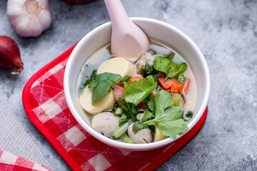 Boiled tofu and minced pork served in white cups with red checkered saucers placed on a white table.