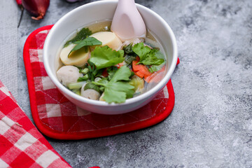 Boiled tofu and minced pork served in white cups with red checkered saucers placed on a white table.
