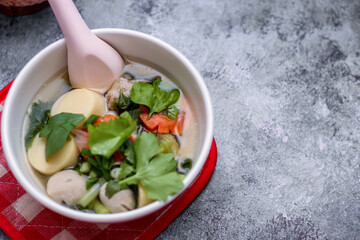 Boiled tofu and minced pork served in white cups with red checkered saucers placed on a white table.