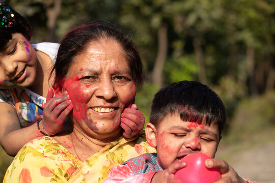 Elderly Indian Lady And Kids Enjoying Holi With Gulal Or Abir Rang Abeer. Festive, Family, Fun, Celebration, Enjoyment, Togetherness, Multi Generation, Relationship, Bonding, Affection, Love Concept