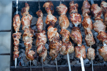 Georgian national dish meat on a spit, grilled on a large metal grill with hot charcoal, the meat is golden brown.