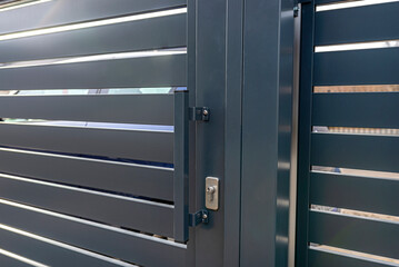 Modern anthracite panel fence, visible sliding gate to the garage, visible handle and lock.