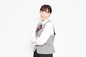 白い背景の前に立って腕組みをしている笑顔のビジネスウーマン 