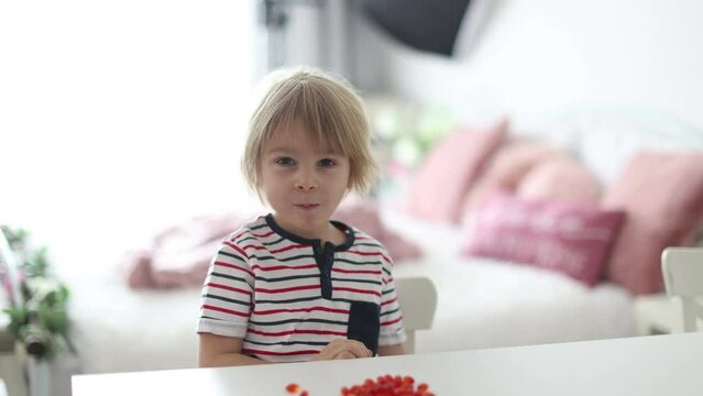 Cute little child, toddler boy, eating alfa omega 3 child suplement vitamin pills at home for better imunity