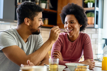 Fototapeta na wymiar Happy african american couple having breakfast together in the kitchen