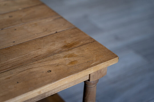 a corner part of a wooden table located on a gray laminate floor.