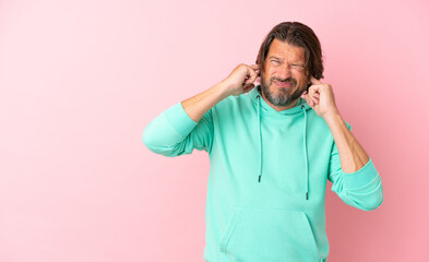 Senior dutch man isolated on pink background frustrated and covering ears