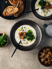 Creamy cauliflower soup on a black bowl top view