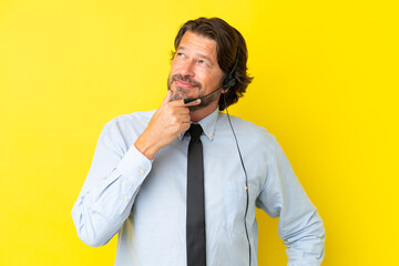 Telemarketer dutch man working with a headset isolated on yellow background looking to the side