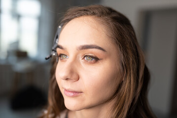 The makeup artist applies eyeliner to the girl with a brush on the upper eyelid and draws an arrow