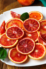 Bloody Sicilian oranges in a white plate on wooden table.