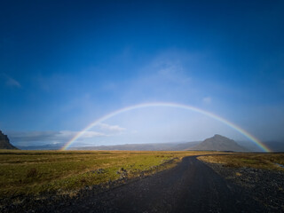 Curved track, rainbow and mountains under clear blue sky