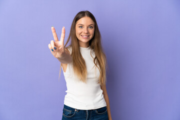 Young Lithuanian woman isolated on purple background smiling and showing victory sign