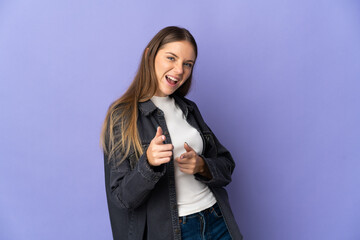 Young Lithuanian woman isolated on purple background pointing to the front and smiling