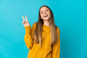 Young Lithuanian woman isolated on blue background smiling and showing victory sign