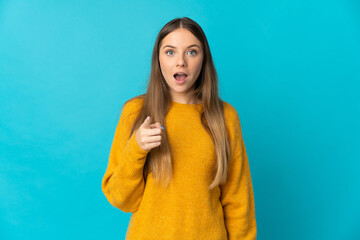 Young Lithuanian woman isolated on blue background surprised and pointing front