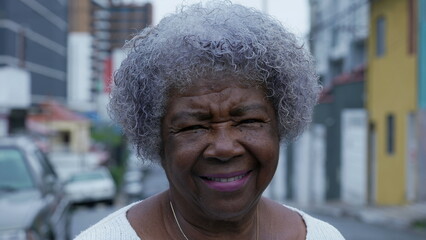 Portrait of a senior African woman with gray hair standing in urban street smiling at camera