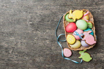 Colorful easter cookies in basket with Multi colors Easter eggs on colored background . Pastel color Easter eggs. holiday concept with copy space