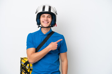 Young caucasian man with thermal backpack isolated on white background pointing to the side to present a product