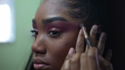 Obraz premium One African girl applying make up in front of mirror