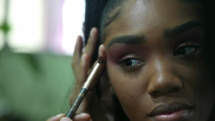 One African girl applying make up in front of mirror