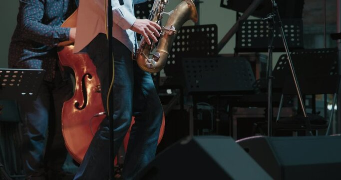 Caucasian men at a concert playing jazz and blues on saxophone and contrabass. Live musical performance and virtuosity of playing strings and wind instruments