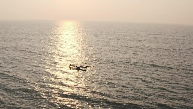 Aerial follow shot of dji drone over the sea into the sunset