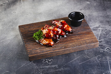 Chicken wings in teriyaki sauce on wooden cutting board