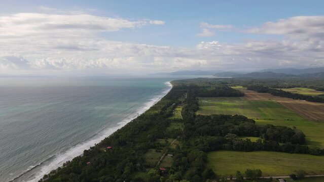 Aerial shot of a beautiful long beach in costa rica. Sunny day close to the pacific ocean and the tropical forest