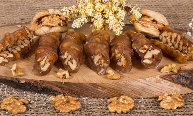 Traditional Turkish dessert; Walnut baton sausage. It is made with grape molasses and walnuts. Walnut sausage on a wooden plate