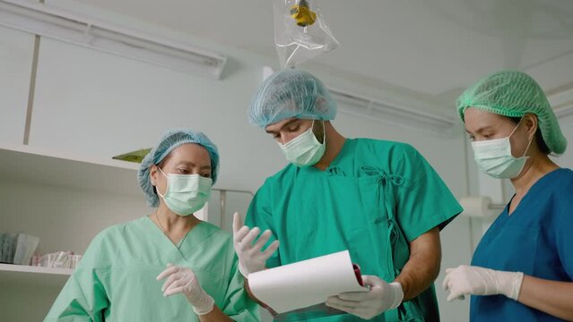 Team Of Doctors And Nurses In The Operating Room Are Consulting The Patient's Condition From The Patient's History Document.
