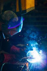 man in workshop working with metal and welding
