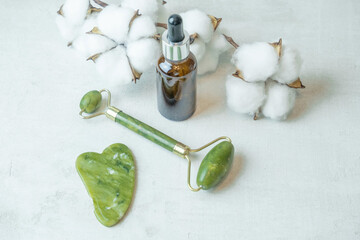 jade roller for facial massage gouache scraper brown bubble with serum , the concept of facial...