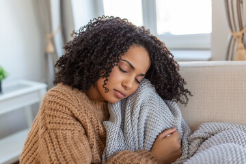 Sick young african woman feeling cold covered with blanket sit on bed, ill black girl shivering...