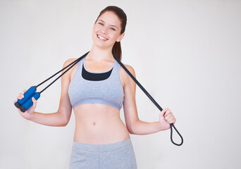 Skipping her way to fitness. Portrait of an attractive young woman holding a skipping rope over her...