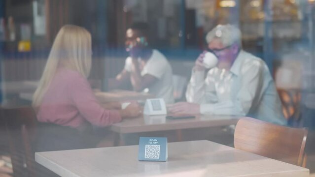 View through window of waiter put qr-code sign on table in cafe. Realtime 
