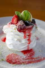 Pavlov dessert with whipped whites and berries on a white plate