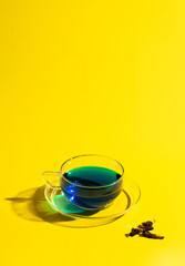  Butterfly tea or blue tea on yellow background with hard light and shadow.  Ayurvedic herbal beverage concept