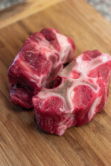 Fresh raw veal or beef leg or neck bones with meat. Soup and stock ingredients, close up shot on wooden kitchen board, no people