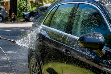 Selective focus shot of washing a black Suv 4wd car with high pressure washer cleaner. Car wash
